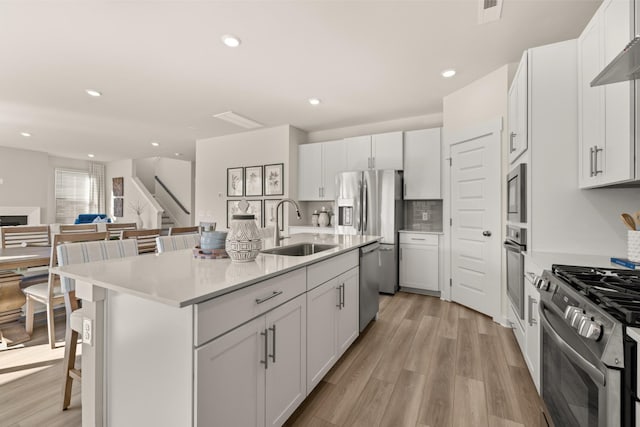 1243 Tucker Dr, Lebanon, TN 37087 - kitchen featuring stainless steel appliances, a breakfast bar, an island with sink, open floor plan, and light wood-style flooring