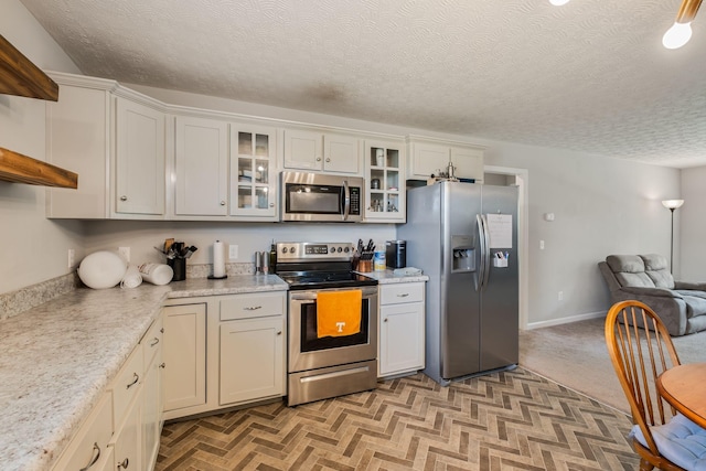 183 Caydras Way, Lafayette, TN 37083 - kitchen featuring appliances with stainless steel finishes, a textured ceiling, light countertops, open floor plan, and glass insert cabinets