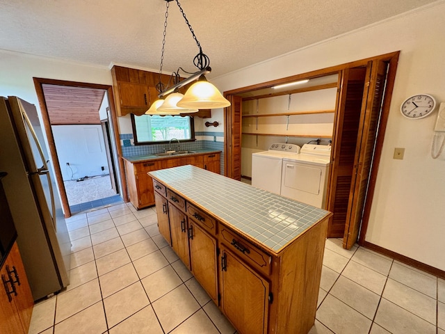 1039 Old Martha Washngton Rd, Clarkrange, TN 38553 - kitchen with washing machine and dryer, tile counters, freestanding refrigerator, brown cabinetry, and tasteful backsplash
