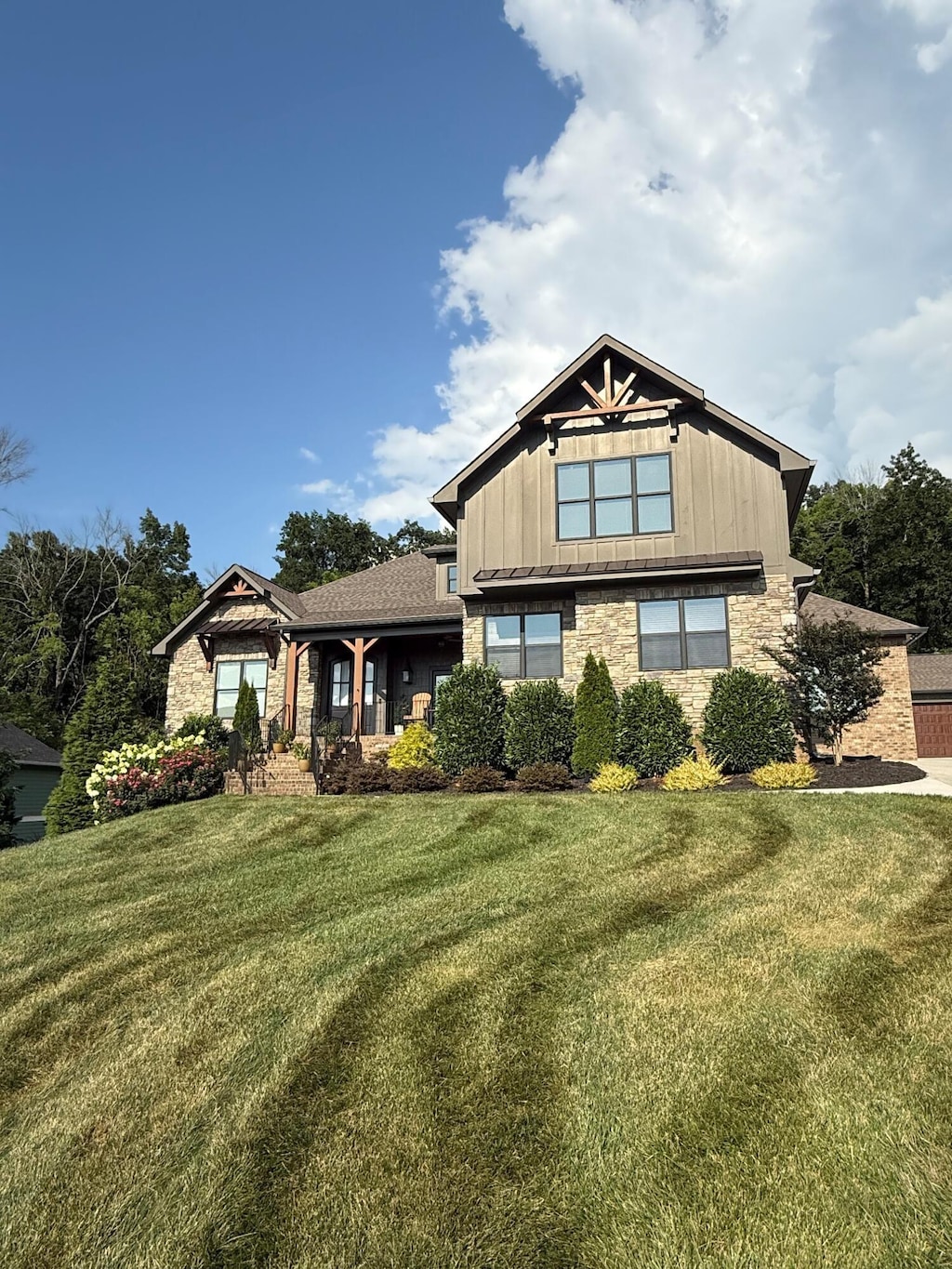 9047 Sunridge Dr, Ooltewah, TN 37363 - view of front of house featuring board and batten siding, a front lawn, and stone siding