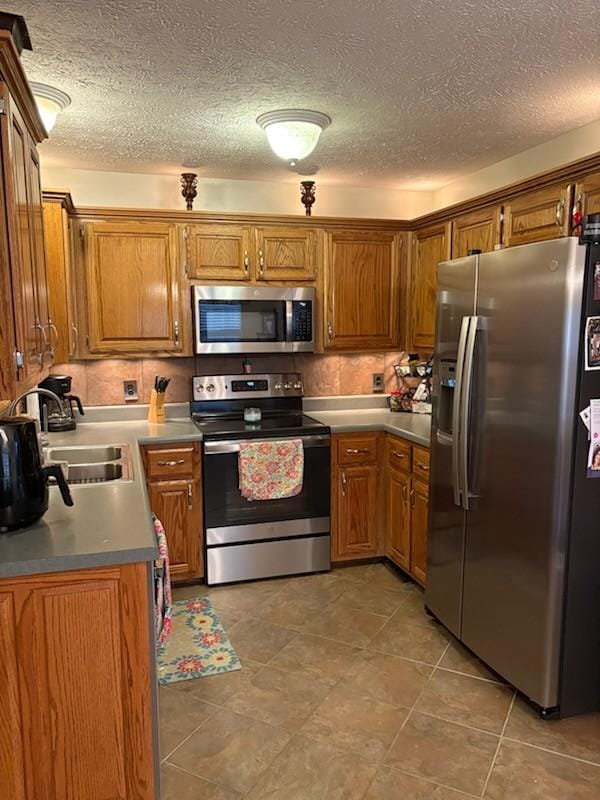 101 Jasmine Way N, Portland, TN 37148 - kitchen featuring stainless steel appliances, brown cabinets, and a textured ceiling