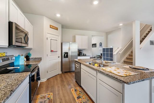 125 Stammer Farms Blvd, Chapel Hill, TN 37034 - kitchen featuring appliances with stainless steel finishes, light wood finished floors, white cabinetry, an island with sink, and light stone countertops