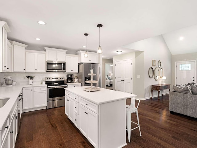 310 Diane Loop, White Bluff, TN 37187 - kitchen featuring stainless steel appliances, a breakfast bar area, decorative backsplash, white cabinets, and dark wood-style floors