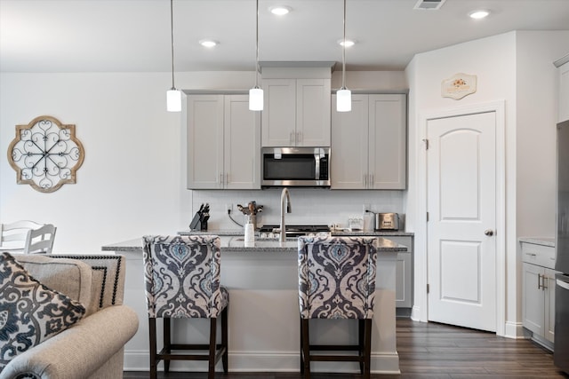 3702 Mathewson Way, Murfreesboro, TN 37128 - kitchen featuring stainless steel microwave, a breakfast bar area, tasteful backsplash, light stone countertops, and a kitchen island with sink