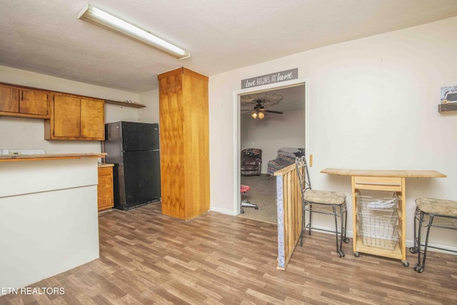 197 Wedgewood Ln, Spring City, TN 37381 - kitchen with freestanding refrigerator, brown cabinets, light wood-type flooring, ceiling fan, and a textured ceiling