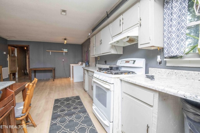 197 Wedgewood Ln, Spring City, TN 37381 - kitchen with gas range gas stove, under cabinet range hood, washer / dryer, white cabinetry, and light wood-style flooring