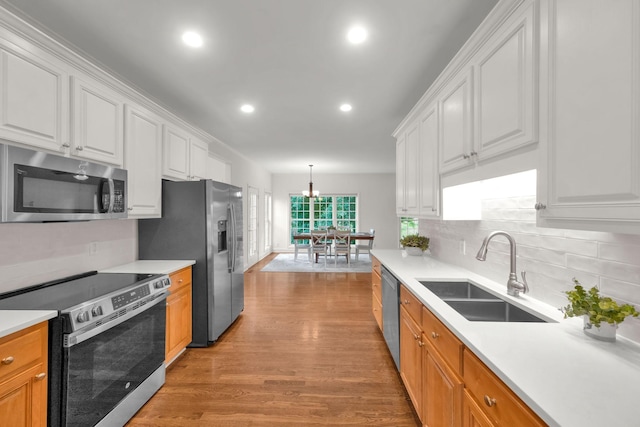 2785 Rutland Ct, Thompsons Station, TN 37179 - kitchen featuring appliances with stainless steel finishes, white cabinets, light wood-style floors, decorative backsplash, and light countertops