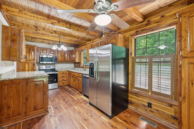 584 Mccord Hollow Rd, Hohenwald, TN 38462 - kitchen with appliances with stainless steel finishes, a wooden ceiling with exposed beams, brown cabinets, a chandelier, and hardwood / wood-style flooring