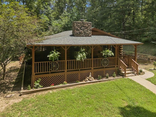 584 Mccord Hollow Rd, Hohenwald, TN 38462 - view of front of home featuring a front lawn, a chimney, a porch, log siding, and roof with shingles