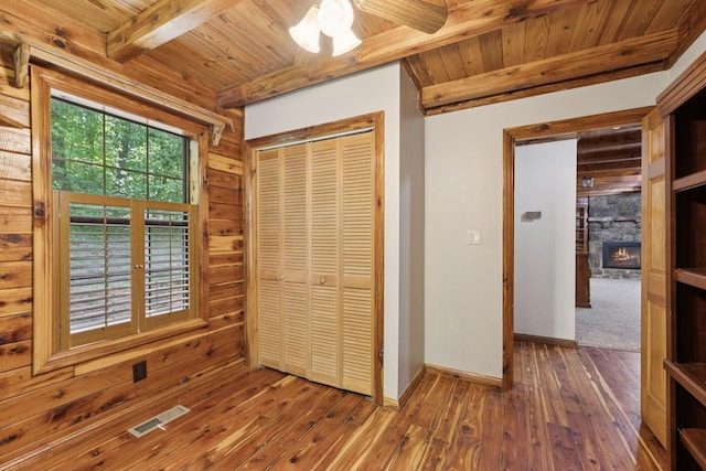 584 Mccord Hollow Rd, Hohenwald, TN 38462 - unfurnished bedroom featuring a wooden ceiling with exposed beams, hardwood / wood-style flooring, a closet, and a stone fireplace