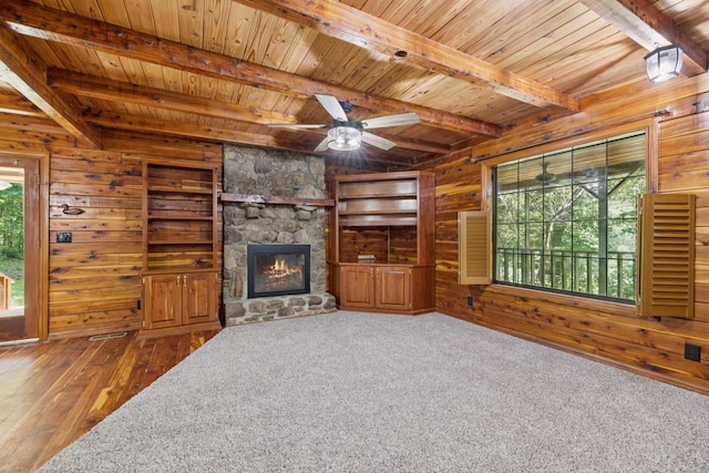 584 Mccord Hollow Rd, Hohenwald, TN 38462 - unfurnished living room with wooden walls, a wood ceiling with exposed beams, ceiling fan, a fireplace, and hardwood / wood-style floors