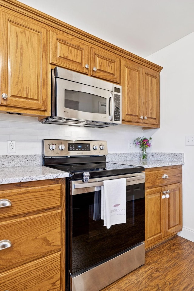 2016 Golden Ct, Spring Hill, TN 37174 - kitchen with stainless steel appliances, brown cabinets, dark wood-style flooring, backsplash, and light stone counters
