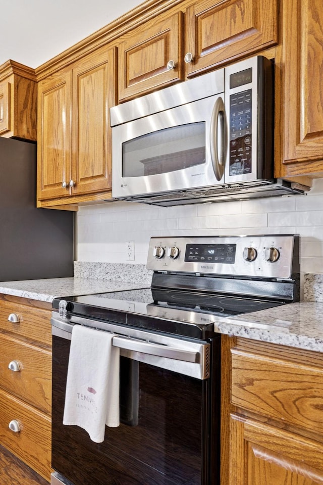 2016 Golden Ct, Spring Hill, TN 37174 - kitchen featuring stainless steel appliances, tasteful backsplash, brown cabinetry, and light stone countertops