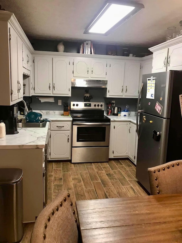 217 Red Oak Rd, Dover, TN 37058 - kitchen featuring stainless steel appliances, under cabinet range hood, white cabinets, and wood finish floors