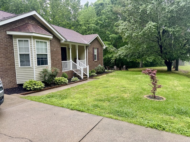 217 Red Oak Rd, Dover, TN 37058 - view of front of home featuring a front lawn, covered porch, brick siding, and a shingled roof