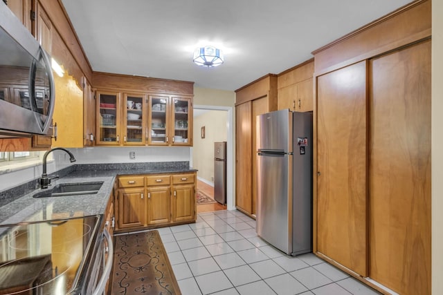 499 Pettus St, Lawrenceburg, TN 38464 - kitchen featuring stainless steel appliances, brown cabinets, light tile patterned floors, glass insert cabinets, and dark stone countertops