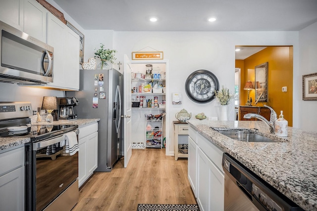 155 Nunally Dr, Baxter, TN 38544 - kitchen featuring appliances with stainless steel finishes, light wood-style flooring, light stone counters, white cabinetry, and recessed lighting