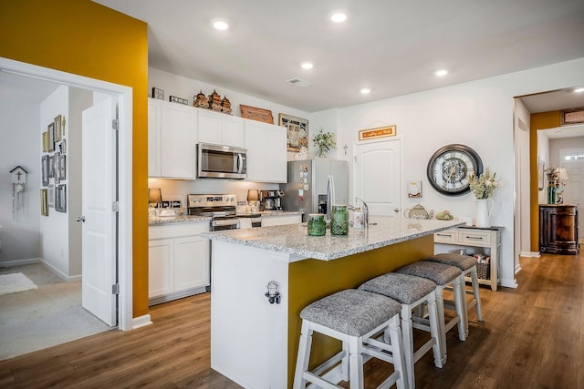 155 Nunally Dr, Baxter, TN 38544 - kitchen with appliances with stainless steel finishes, a kitchen island with sink, white cabinetry, a breakfast bar, and wood finished floors