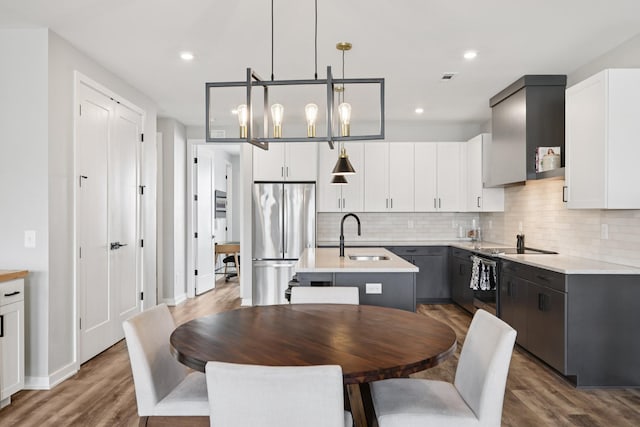 2006 Edison Park Ln, Nashville, TN 37209 - kitchen featuring stainless steel appliances, a center island with sink, decorative backsplash, light countertops, and wood finished floors