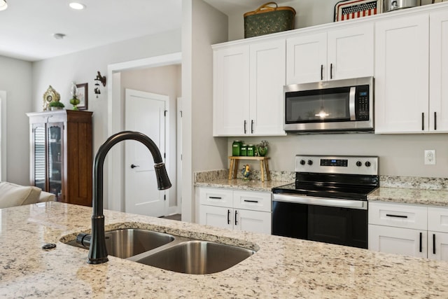 26 Sycamore Rdg W, Burns, TN 37029 - kitchen featuring appliances with stainless steel finishes, white cabinets, light stone countertops, and recessed lighting