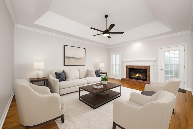 1436 Cheshire Pl, Murfreesboro, TN 37129 - living area featuring a tray ceiling, a ceiling fan, wood finished floors, a brick fireplace, and crown molding