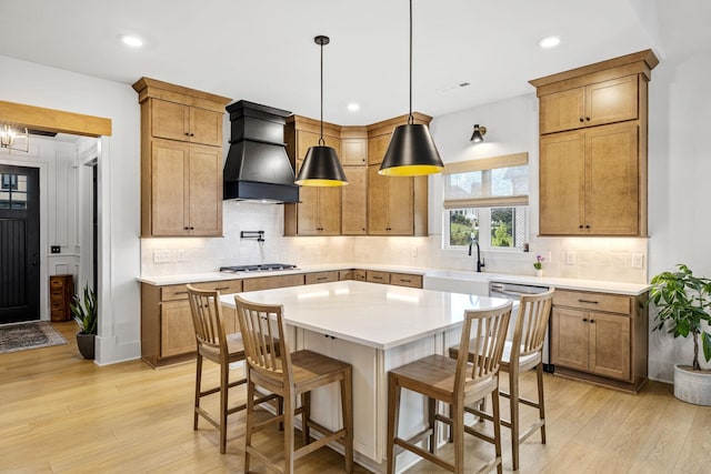 5831 Branta Dr, Franklin, TN 37064 - kitchen featuring light wood-style floors, stainless steel appliances, premium range hood, a breakfast bar area, and light countertops