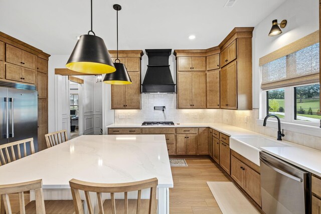 5831 Branta Dr, Franklin, TN 37064 - kitchen featuring custom exhaust hood, stainless steel appliances, light wood finished floors, tasteful backsplash, and hanging light fixtures
