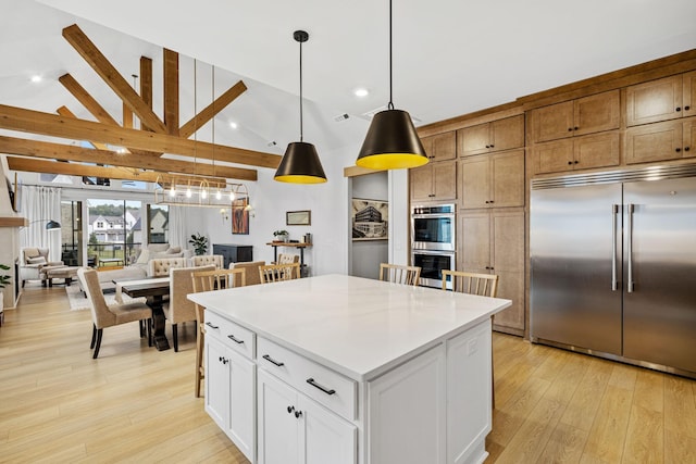 5831 Branta Dr, Franklin, TN 37064 - kitchen with appliances with stainless steel finishes, a kitchen island, light wood-style floors, lofted ceiling, and decorative light fixtures