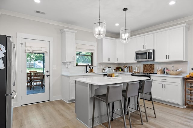 8408 Morin Rd, Chattanooga, TN 37421 - kitchen with stainless steel appliances, light countertops, white cabinetry, a breakfast bar area, and ornamental molding