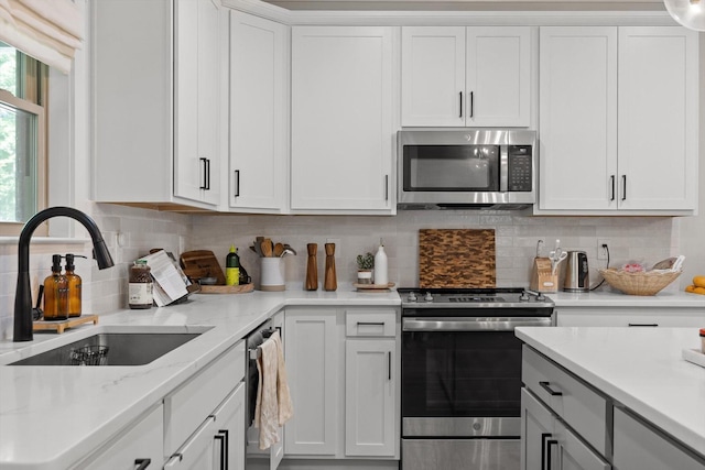 8408 Morin Rd, Chattanooga, TN 37421 - kitchen featuring stainless steel appliances, white cabinetry, decorative backsplash, and light stone countertops