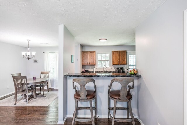 112 Ray Ave, Old Hickory, TN 37138 - kitchen with brown cabinetry, dark countertops, a chandelier, dark wood-style flooring, and a breakfast bar area