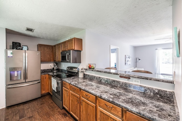 112 Ray Ave, Old Hickory, TN 37138 - kitchen featuring stainless steel appliances, dark wood-type flooring, brown cabinets, dark stone countertops, and a textured ceiling