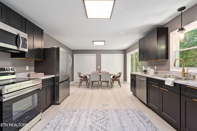 588 Meadowbrook Dr, Mcminnville, TN 37110 - kitchen featuring stainless steel appliances, light wood-style flooring, light countertops, decorative light fixtures, and dark cabinets