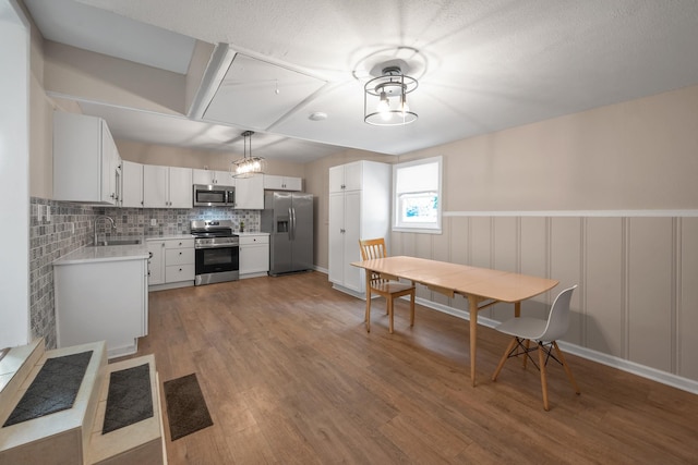 909 Woods Lake Dr, Madison, TN 37115 - kitchen featuring appliances with stainless steel finishes, light countertops, light wood-style flooring, backsplash, and decorative light fixtures