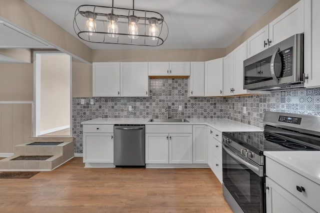 909 Woods Lake Dr, Madison, TN 37115 - kitchen with stainless steel appliances, light countertops, white cabinetry, and a wainscoted wall