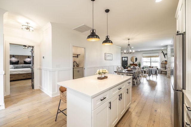 1446 Littleton Ranch Rd, Castalian Springs, TN 37031 - kitchen with freestanding refrigerator, white cabinetry, open floor plan, light wood-style floors, and a wainscoted wall