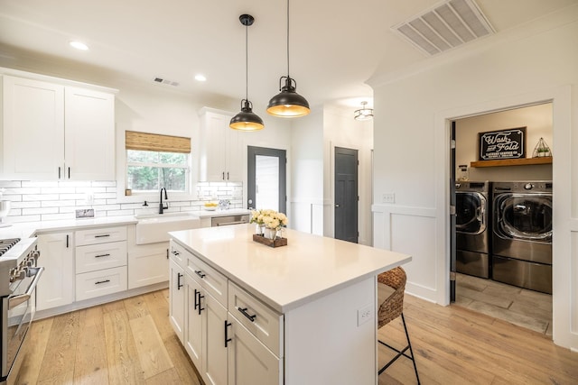 1446 Littleton Ranch Rd, Castalian Springs, TN 37031 - kitchen featuring washer and clothes dryer, stainless steel appliances, a kitchen breakfast bar, light wood-type flooring, and wainscoting