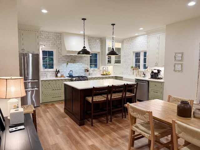 1782 Honey Ln, Estill Springs, TN 37330 - kitchen with stainless steel appliances, backsplash, light countertops, custom range hood, and a kitchen bar