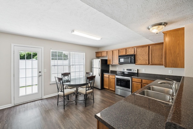 3138 Prater Ct, Murfreesboro, TN 37128 - kitchen featuring appliances with stainless steel finishes, brown cabinetry, dark countertops, dark wood-style floors, and a textured ceiling