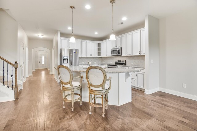 835 Meadowcrest Way, Lebanon, TN 37090 - kitchen featuring appliances with stainless steel finishes, arched walkways, white cabinets, decorative backsplash, and light wood finished floors