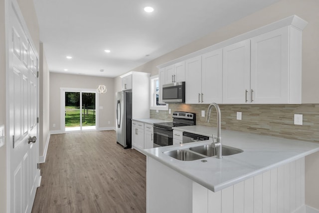 1104 Bridge St, Columbia, TN 38401 - kitchen with stainless steel appliances, backsplash, light countertops, wood finished floors, and white cabinetry