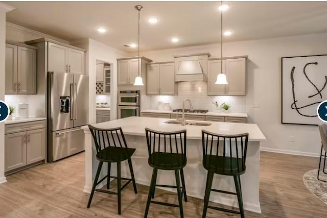 3397 Tucker Trce, Columbia, TN 38401 - kitchen with appliances with stainless steel finishes, a kitchen island with sink, light countertops, decorative backsplash, and light wood-style floors