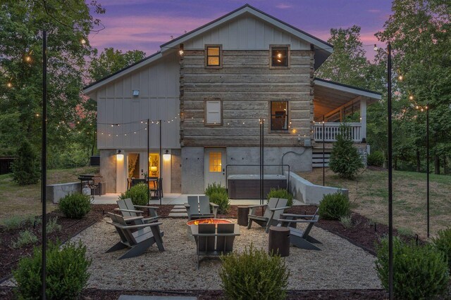 8014 Shoals Branch Rd, Primm Springs, TN 38476 - back of property at dusk featuring an outdoor fire pit, a hot tub, a patio area, and board and batten siding