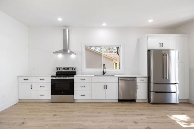 1905 Highland Ave, Columbia, TN 38401 - kitchen featuring appliances with stainless steel finishes, wall chimney exhaust hood, white cabinets, light wood-type flooring, and light countertops