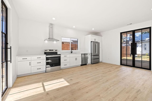 1905 Highland Ave, Columbia, TN 38401 - kitchen with appliances with stainless steel finishes, wall chimney exhaust hood, light wood finished floors, white cabinetry, and light countertops