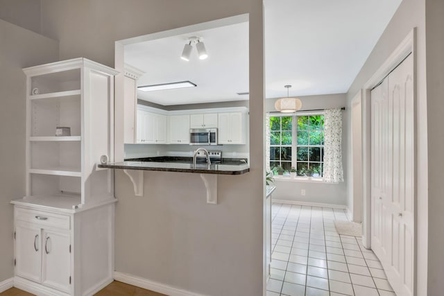 2910 Churchill Ln, Thompsons Station, TN 37179 - kitchen featuring stainless steel microwave, open shelves, a kitchen breakfast bar, white cabinets, and light tile patterned floors