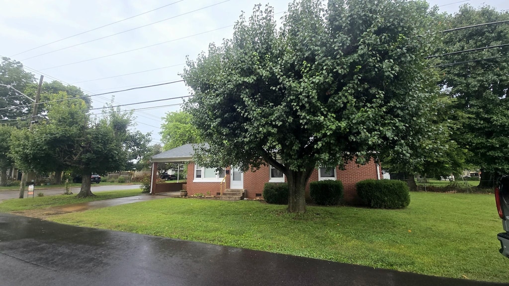 501 6th St, Lawrenceburg, TN 38464 - view of front facade featuring a front yard, brick siding, entry steps, an attached carport, and driveway