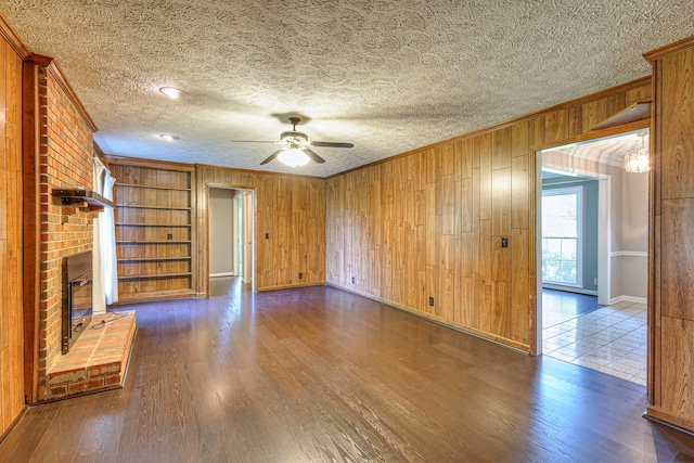 2010 Hartland Rd, Franklin, TN 37069 - unfurnished living room with ornamental molding, ceiling fan, wooden walls, dark wood-style floors, and a fireplace