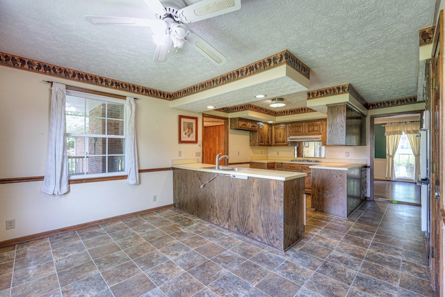 2010 Hartland Rd, Franklin, TN 37069 - kitchen featuring a peninsula, a textured ceiling, light countertops, a ceiling fan, and brown cabinetry
