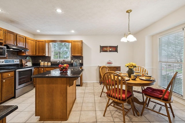 217 Fox Hunt Ln, Lebanon, TN 37087 - kitchen featuring appliances with stainless steel finishes, under cabinet range hood, tasteful backsplash, a kitchen island, and brown cabinetry